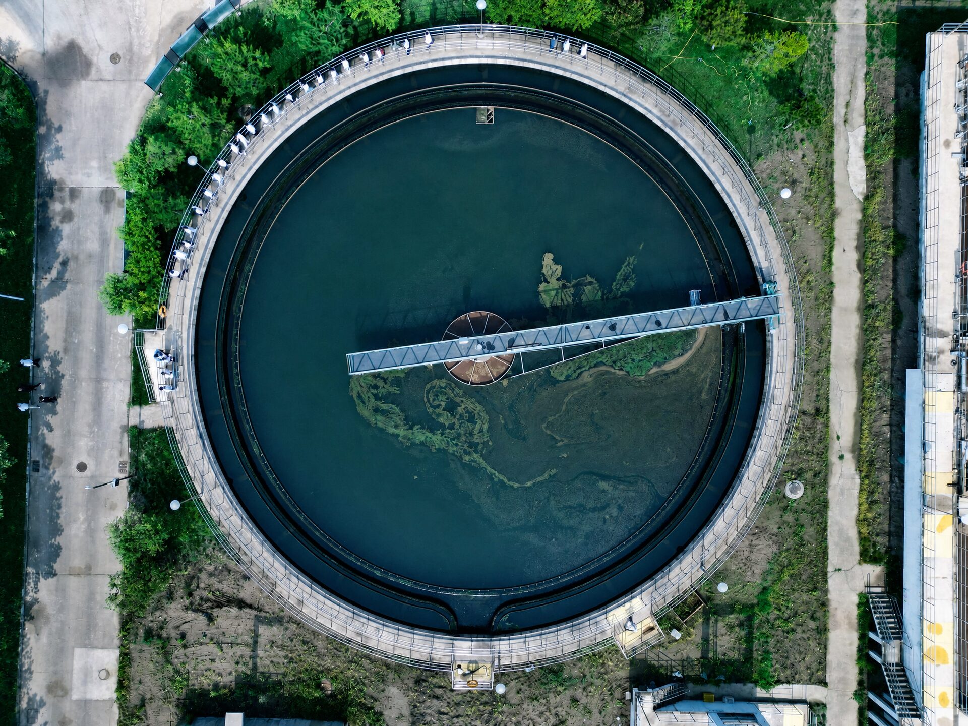 Aerial top view of a circular secondary clarifier with a rotating scraper bridge at a wastewater treatment plant